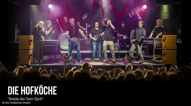 Die Hofköche stehen auf der Bühne vor eine Menschenmenge und performen ihren Song 'Smells like Team Spirit'.