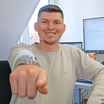 Mitarbeiter zeigt Kamera entgegen